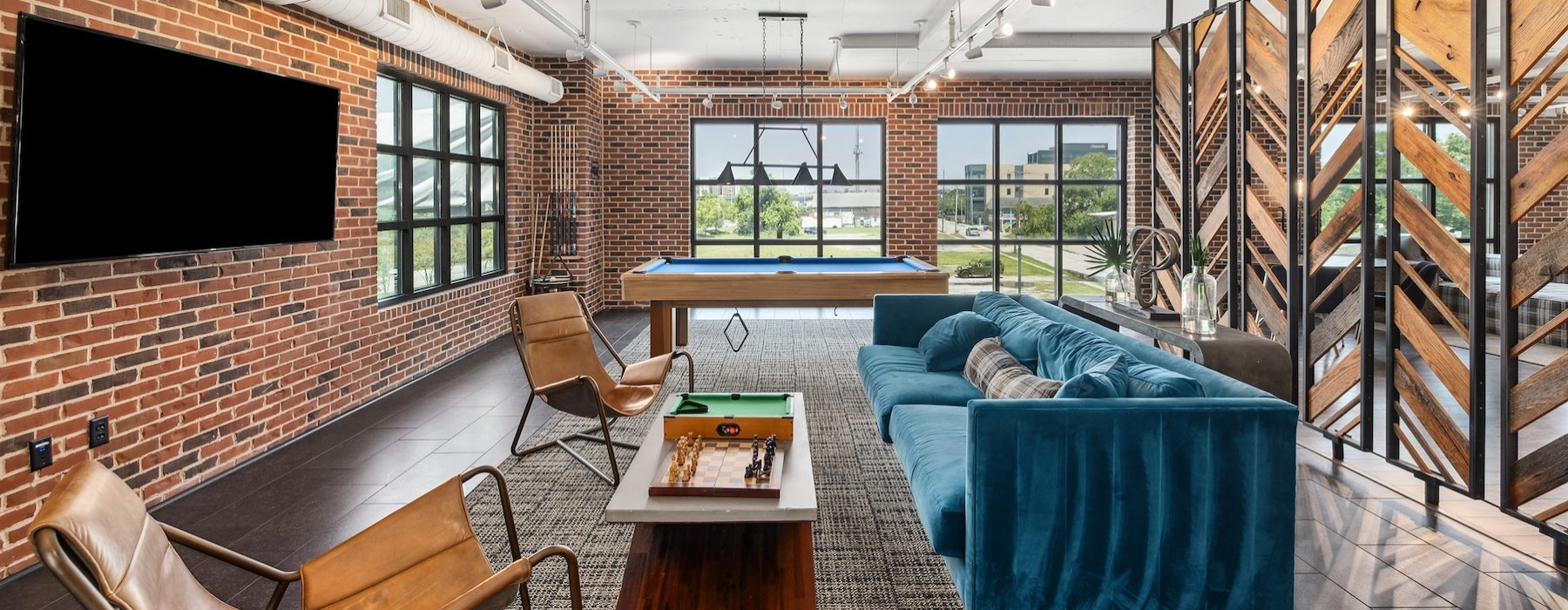 a clubroom with a tv, table, couch and chairs